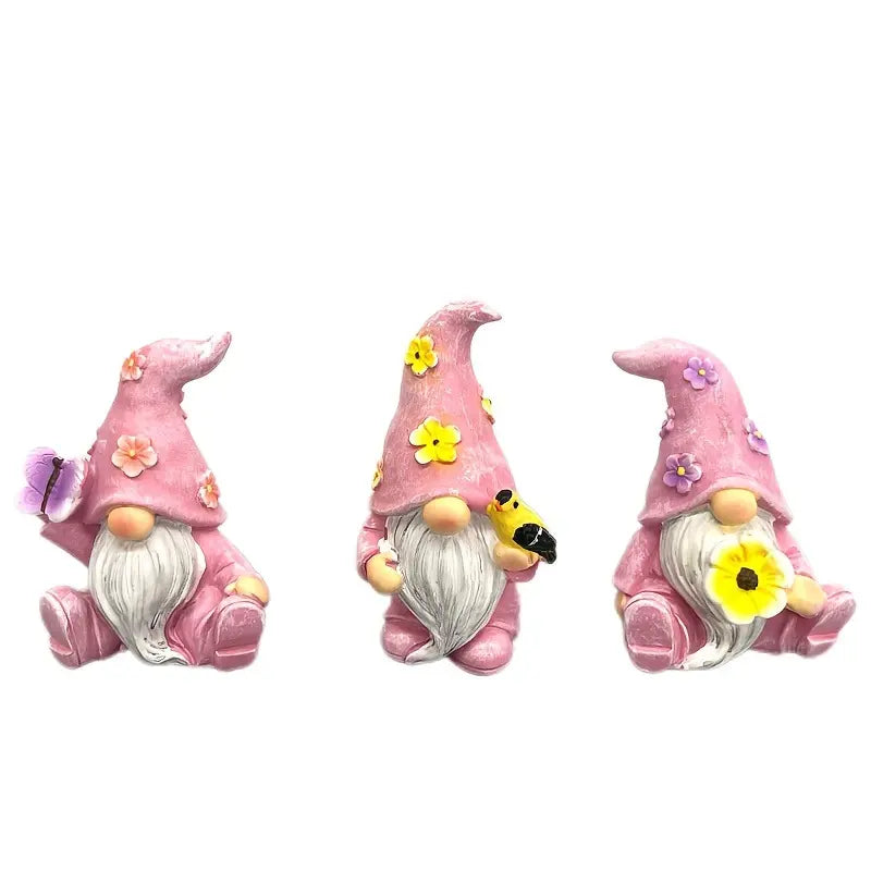 Three pink gnomes with white beards, flower hats, holding flowers and a bee, on a white background.
