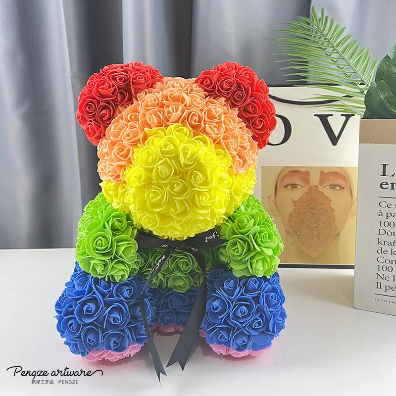 Colorful teddy bear made of roses in rainbow hues, with a black ribbon, on a table.