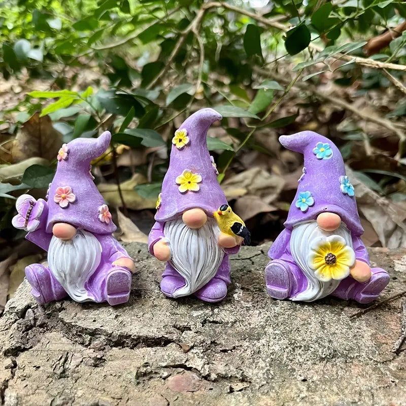 Three purple-hatted gnomes with flowers, sitting on a textured surface, surrounded by greenery.