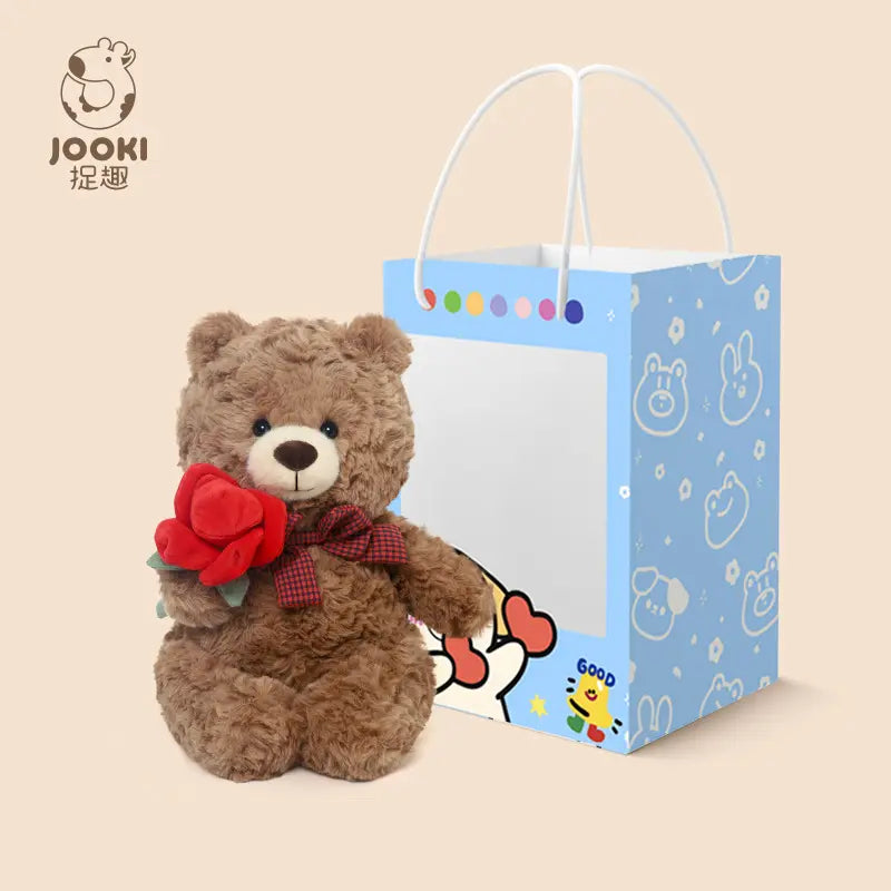 Brown teddy bear with red roses sits next to a blue gift bag with cartoon characters.