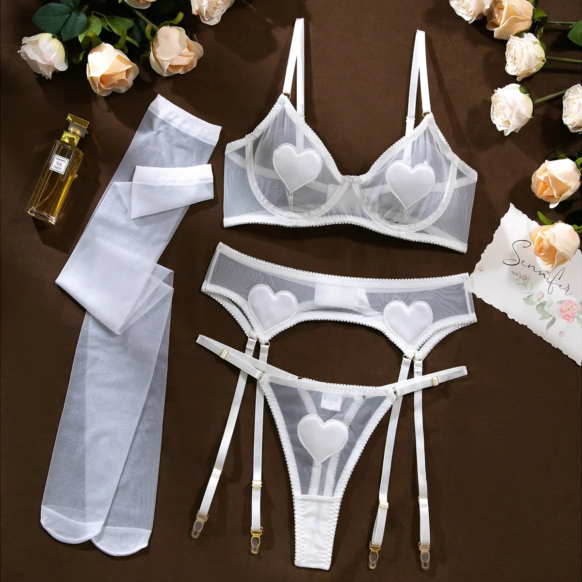White lingerie set with heart patterns on a dark background, surrounded by white roses.