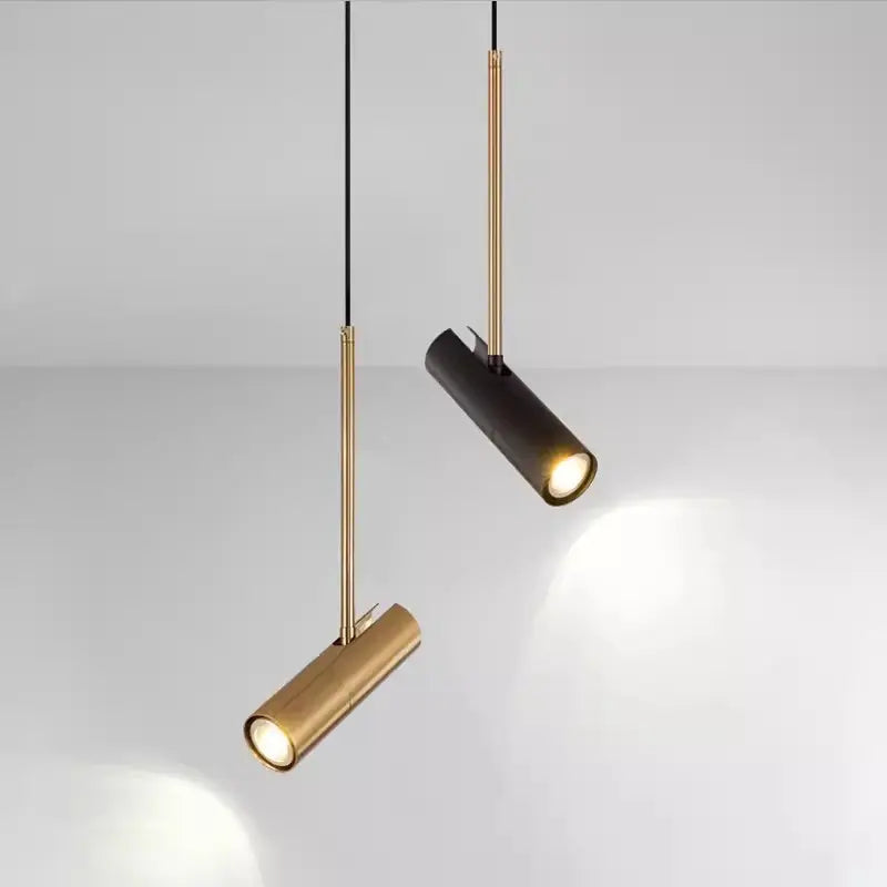 Two pendant lights, one gold and one black, with cylindrical shades, hang from the ceiling.