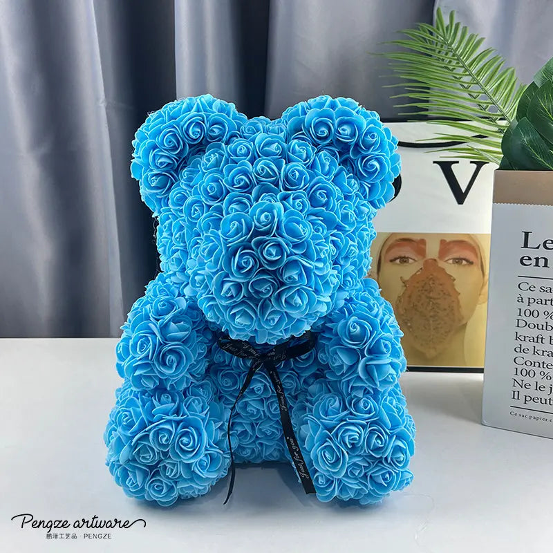 Blue teddy bear made of roses with a black ribbon, set against a modern indoor background.