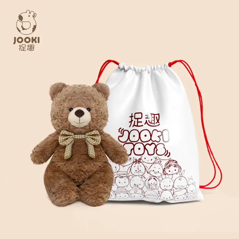 Brown teddy bear with a bow tie next to a white drawstring bag with red accents and cartoon designs.