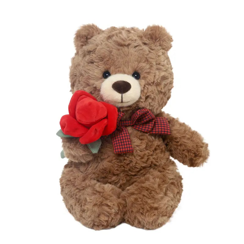 A fluffy brown teddy bear with a plaid bow holds a red fabric rose.
