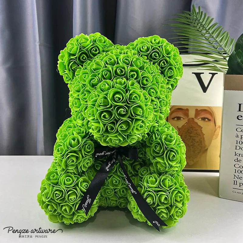 Green rose-covered teddy bear with black ribbon, set against a modern background with books and plants.