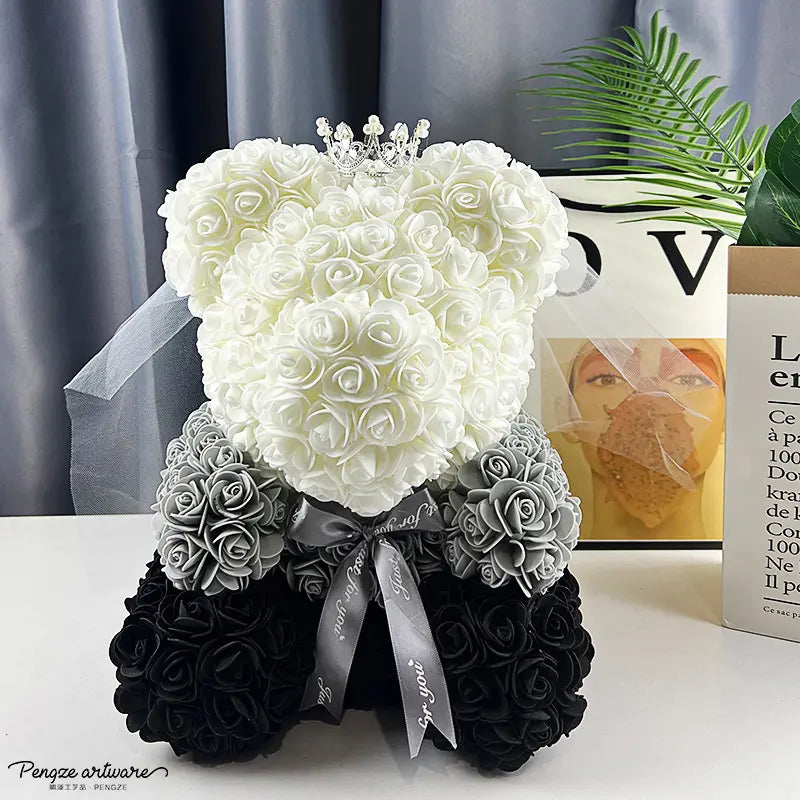 Bear-shaped rose sculpture with white, gray, and black roses, a pearl crown, and a ribbon bow.