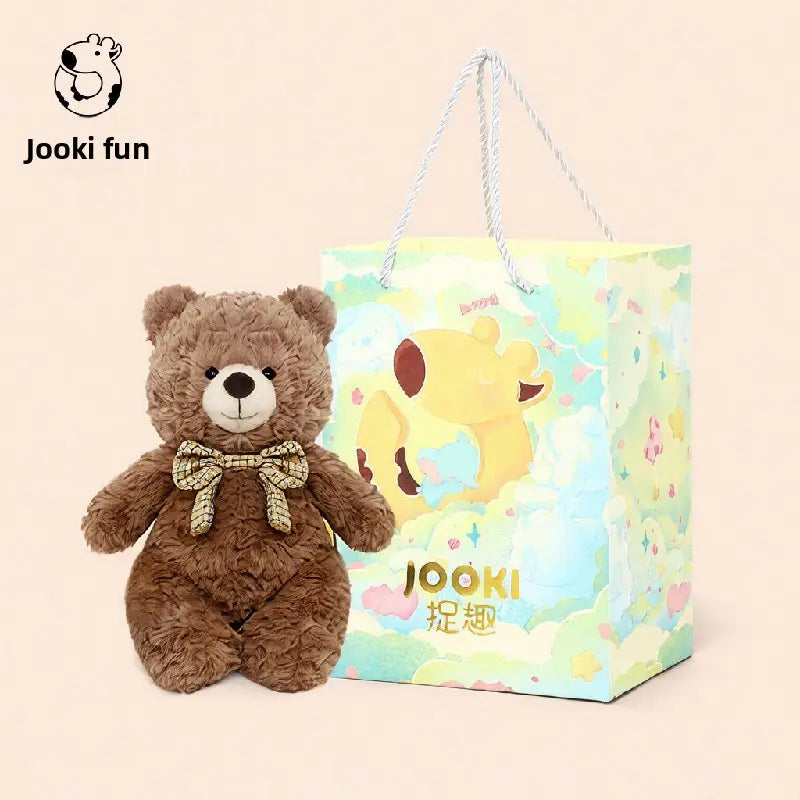 Brown teddy bear with a bow tie next to a colorful gift bag featuring playful animal illustrations.