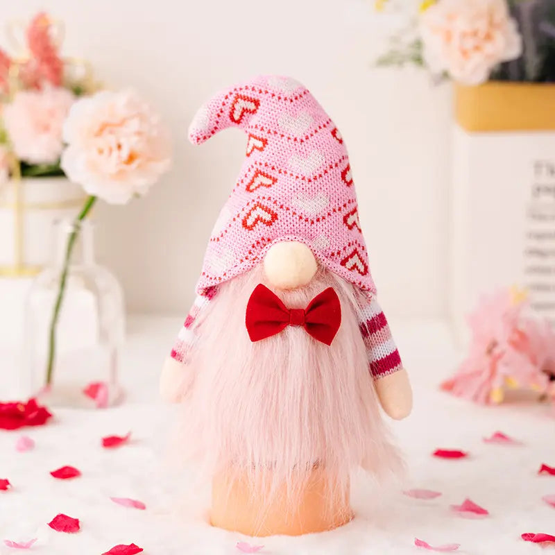 A gnome with a pink heart hat, fluffy beard, red bow tie, surrounded by flowers and petals.