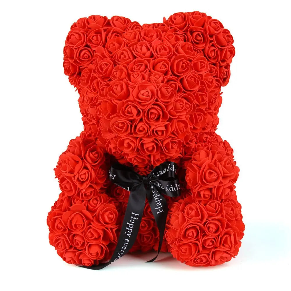 Red teddy bear made of roses, with a black ribbon bow at the neck, on a white background.